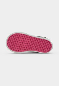 Semelle de chaussure avec motif gaufré rose et bord extérieur blanc sur un fond clair uni.