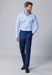 Lichtblauw button-up shirt, marineblauwe broek, medium fit, gladde stof, met een klassieke kraag en een lichte textuur. Zwarte schoenen maken de look compleet.