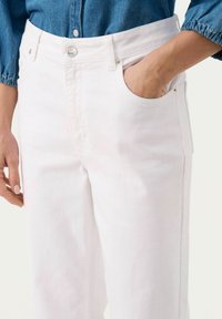 Vita denimbyxor med hög midja, femfickorsdesign och detaljer i silverknappar; mjukt material med en lätt stretch.