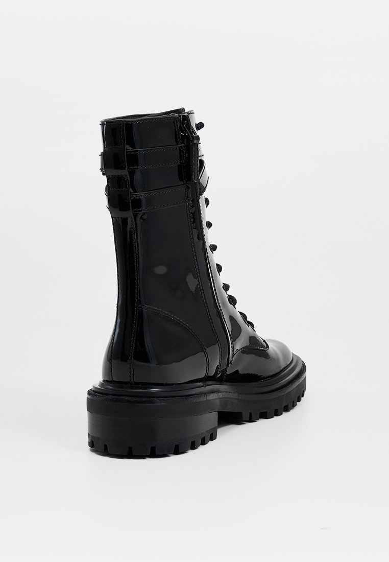 Schwarze lacked Lederstiefel im Combat-Stil mit Schnürung vorne, runder Zehenform und dicker Gummisohle. Sie verfügen über einen seitlichen Reißverschluss und strukturierte Akzente.