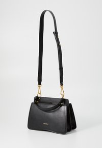 Black leather handbag with a structured design, gold hardware accents, detachable shoulder strap, and a zippered pocket on the back.