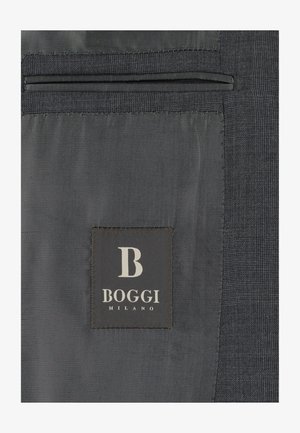 Intérieur d'une veste de costume gris foncé avec une poche et une étiquette noire cousue à l'intérieur portant l'inscription "B Boggi Milano".