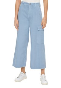 Himmelblaue Cargo-Hosen mit weitem Bein, ausgestattet mit einer Seitentasche, subtilen Steppdetails und kombiniert mit weißen Sneakern.