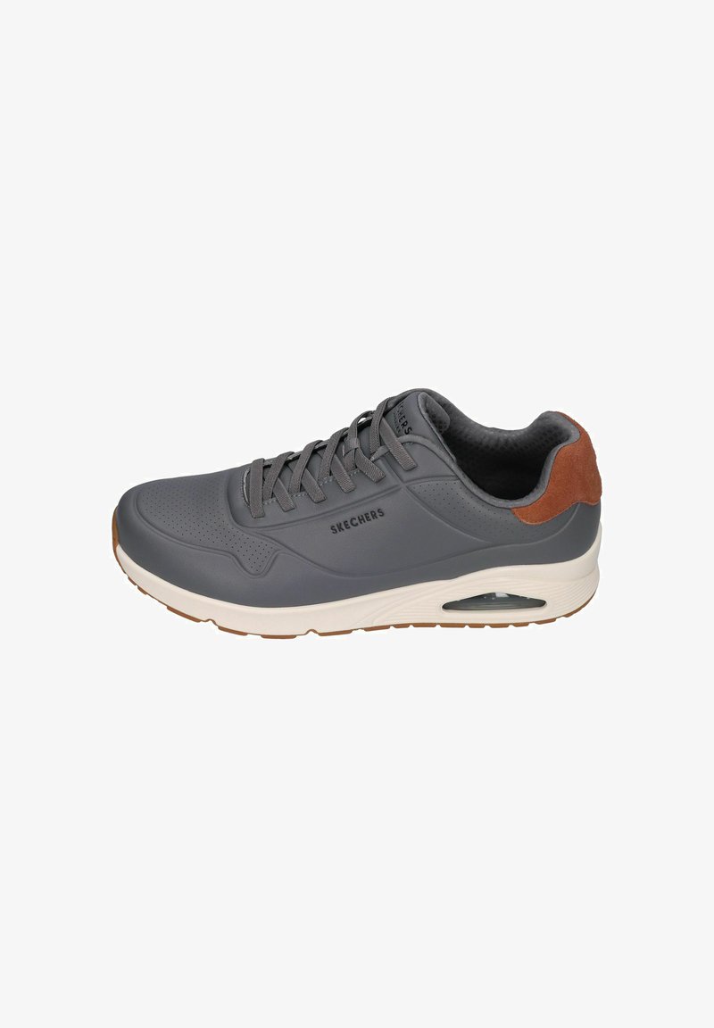 Zapatilla deportiva gris con una parte superior sintética suave, patrón perforado, acento en cuero de gamuza marrón en el talón y suela blanca con aire amortiguado.