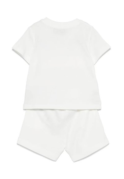 T-shirt bianco in cotone a manica corta abbinato a pantaloni bermuda dello stesso colore. Design semplice, texture morbida e senza motivi o accenti visibili.