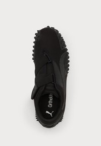 Zapatilla deportiva negra con parte superior de malla texturizada, correas de Velcro y suela exterior con picos de goma para tracción. Plantilla Ortholite visible en el interior.