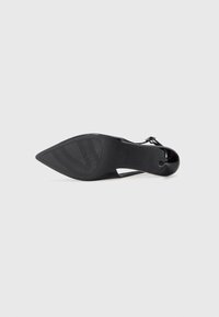 Black patent leather high-heeled shoe with a pointed toe, sleek shape, and textured sole. Features an adjustable strap near the ankle.