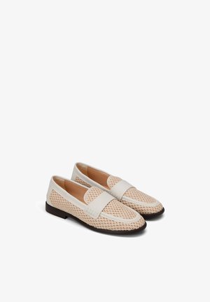 Paire de mocassins tissés beiges avec garniture en cuir blanc et semelles marron foncé, présentés côte à côte sur un fond blanc.