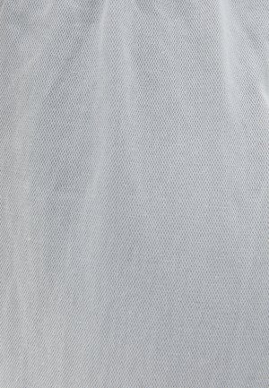 Tissu gris clair avec un motif tissé texturé. La surface a un léger éclat, soulignant sa qualité respirante et sa texture douce.