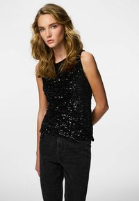 Svart ermelaust topp dekket med små paljetter, med en glatt tekstur og tettsittende design. Kombinert med svarte, høytlivde jeans.