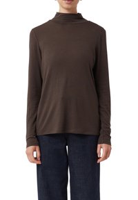 Braunes Langarm-Turtleneck-Oberteil aus weichem Stoff, mit lockerer Passform und glatter Textur, kombiniert mit dunklen Jeans.