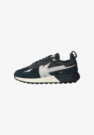 Donkerblauwe en grijze sneaker met witte accenten, zwarte zool en "99" gedrukt in goud nabij de hiel, gezien vanaf de zijkant.