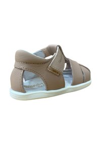 Sandalia de cuero beige con diseño abierto, tira de velcro, suela blanca y acentos texturizados. Presenta un interior acolchado para mayor comodidad.