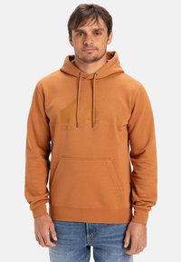 Hætte sweatshirt i brændt orange, med en kengurulomme, snore og et diskret logo print på brystet. Stofblanding af bomuld.