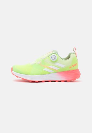 Lys grøn Adidas Terrex trail løbesko med hvide striber, rød sål og drejelås, set fra siden på hvid baggrund.