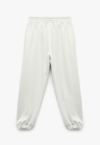 Lys grå sweatpants med elastisk talje og elastiske manchetter ved anklerne, lavet af blødt stof med en glat tekstur.