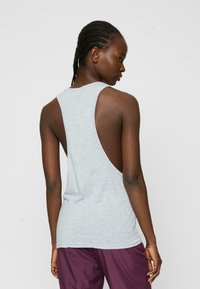 Grå ärmlös tanktop med öppen rygg, tillverkad av lättviktsmaterial. Har en avslappnad passform och en jämn textur.
