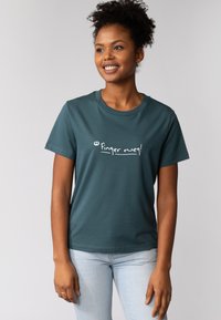 Türkiser Baumwoll-T-Shirt mit kurzen Ärmeln und weißem Text, der auf der Vorderseite "Finger weg!" lautet. Klassisches Rundhals-Design, samtige Textur.