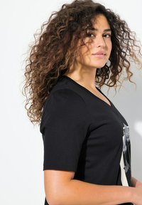 Camiseta de algodón negra con escote en V y mangas cortas, con un estampado gráfico en la parte delantera. Textura suave y diseño sencillo.