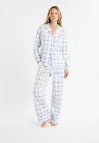 Ensemble pyjama à carreaux en tissu léger ; motifs à carreaux bleus sur fond blanc, chemise boutonnée et pantalon ample.