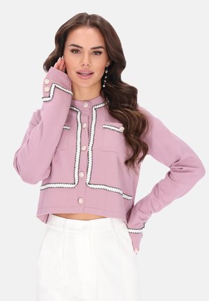 Gekürzter rosa Cardigan mit weißem Rand, rundem Kragen und Knopfverschluss. Verfügt über zwei Fronttaschen und dekorative Knöpfe. Weicher Strickstoff.