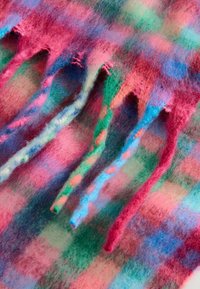Mehrfarbiger Wollstrick in Pink-, Blau-, Grün- und Rottönen. Besitzt strukturierte Stränge mit ausgefransten Kanten, die ein weiches, geschichtetes Aussehen erzeugen.