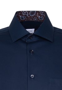 Donkerblauw overhemd met een contrasterend bruin paisleypatroon aan de binnenkant van de kraag. Voorzien van een standaardkraag en knoopsluiting.