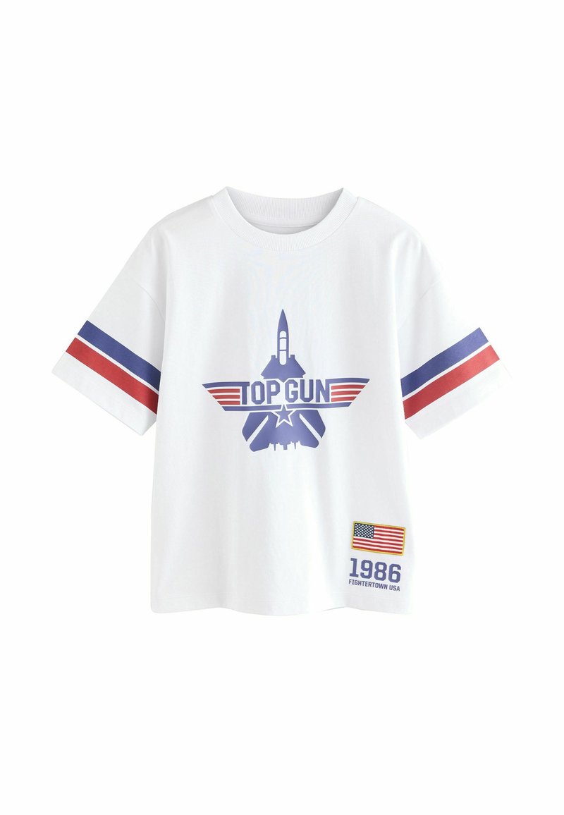 Fehér pamut póló, kék "TOP GUN" grafikával, amelyen rakéta és vadászgép látható. Piros és kék csíkok a ujjakon, 1986-os jelvény zászlóval.