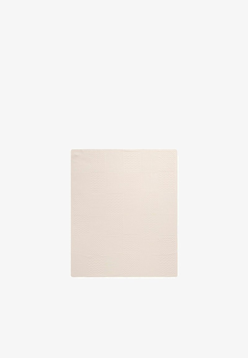 Tapis de bain carré beige avec un motif subtil à carreaux texturé de lignes ondulées et droites.