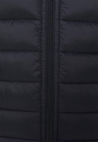 Schwarze Steppjacke mit zentralem Reißverschluss, gesteppter Optik und glatter Oberfläche mit horizontalen Steppnähten.