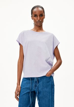 T-shirt lavanda a maniche corte con vestibilità rilassata e collo rotondo, realizzata in tessuto morbido, abbinata a pantaloni in denim blu a vita alta.
