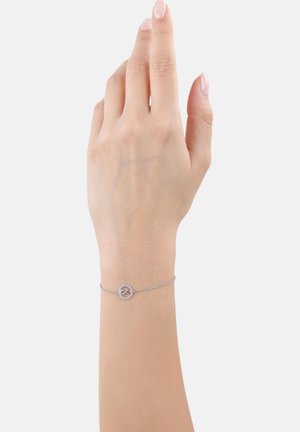 Bracciale a catena argentata con un pendente circolare caratterizzato da piccole pietre trasparenti. La catena è delicata, creando un design sottile.