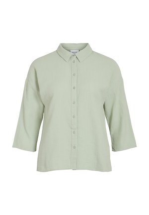 Chemise verte claire à boutonner avec un tissu texturé, un col et des manches trois quarts. Présente une coupe droite et une fermeture à boutons à l'avant.