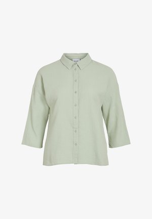 Chemise verte claire à boutonner avec un tissu texturé, un col et des manches trois quarts. Présente une coupe droite et une fermeture à boutons à l'avant.