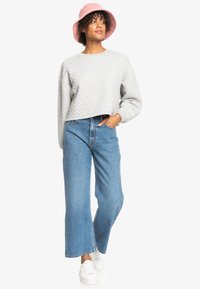 Gray quilted sweater, blue wide-leg jeans, and white sneakers. Accessorized with a pink bucket hat. Casual, relaxed fit.