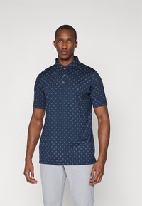 Camisa polo navy de manga corta, con botones en la parte delantera y un patrón de estrellas verdes; textura suave con un pequeño logo en el pecho.