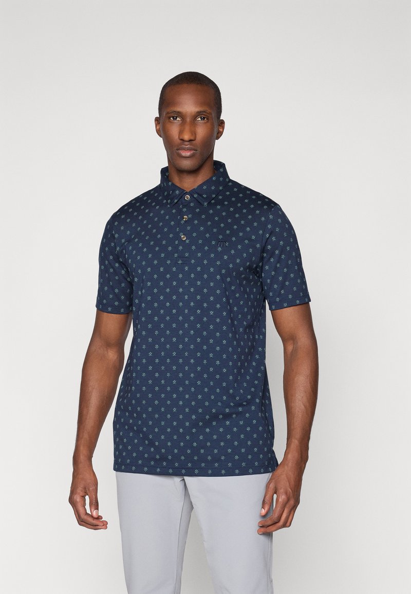 Camisa polo navy de manga corta, con botones en la parte delantera y un patrón de estrellas verdes; textura suave con un pequeño logo en el pecho.