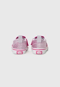 Baskets à paillettes roses avec une semelle blanche, des sangles Velcro et des talons rembourrés ; elles présentent un logo à l'arrière et une finition texturée.