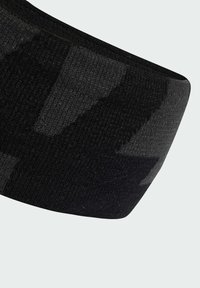 Čierny textilný pás s tkanou štruktúrou, s jemným vzorom v štýle kamufláže a hladkým okrajom. Ideálny na šport alebo neformálne nosenie.