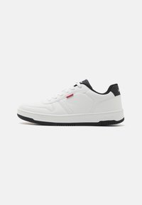 Vit sneaker med en texturerad läderöverdel, svarta accenter vid hälen och en gummisul. Har en snörningsdesign och varumärkeselement.
