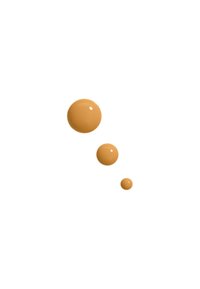 Tre glänsande droppar av beige vätska, varierande i storlek, mot en vit bakgrund. Texturen är slät med en skinande yta.