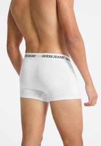 Slip nere in cotone con un elastico bianco "GUESS JEANS", vestibilità aderente, texture liscia e design minimalista.
