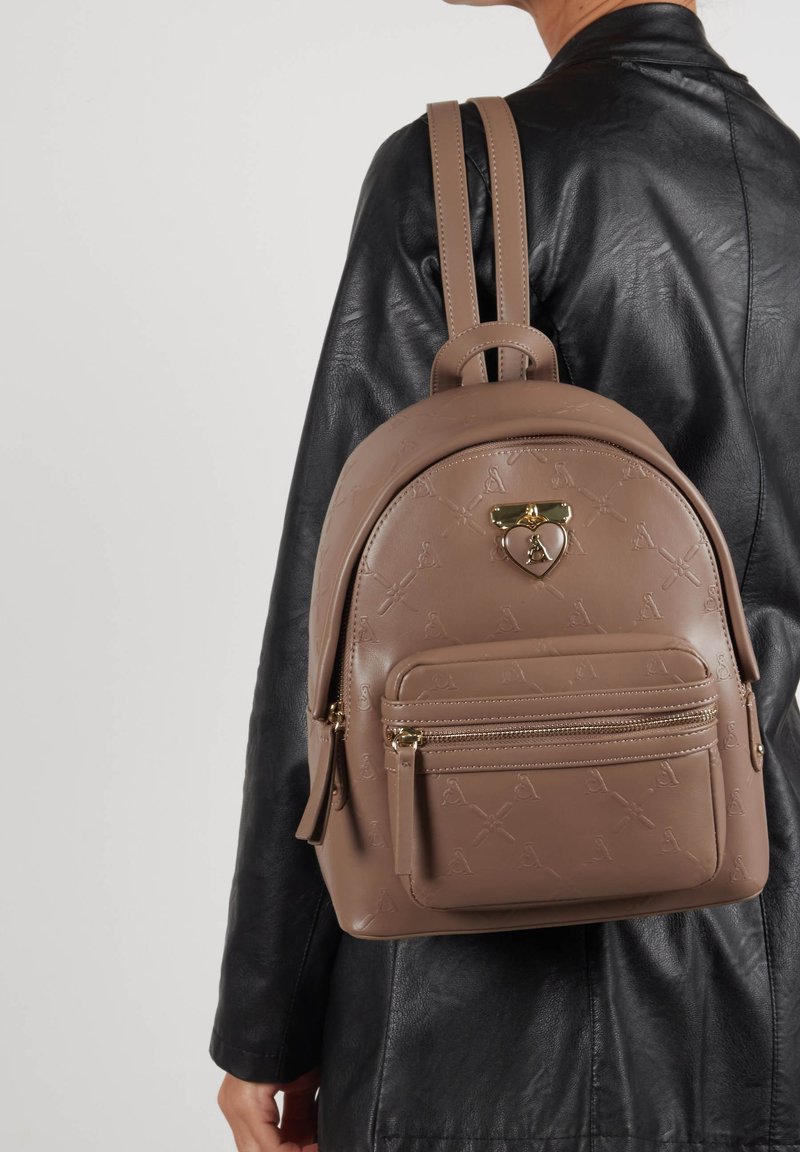 Brązowy plecak z faux skóry z wytłoczonym wzorem, z złotymi detalami, górnym uchwytem i przednią kieszenią na zamek. Podwójne naramienne paski.