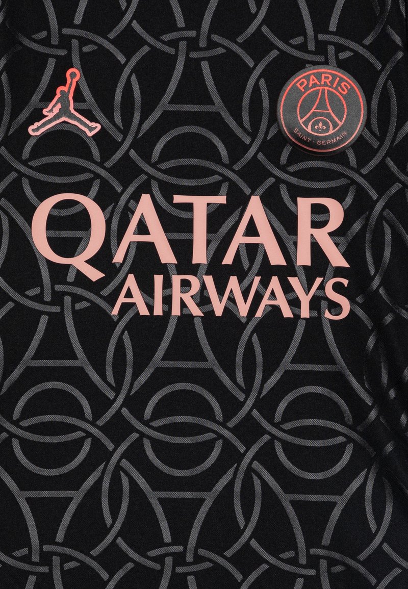 Schwarzer Jersey-Stoff mit einem grauen kreisförmigen Muster, pinkem "QATAR AIRWAYS"-Text, pinkem Jordan-Logo und einem runden PSG-Abzeichen.