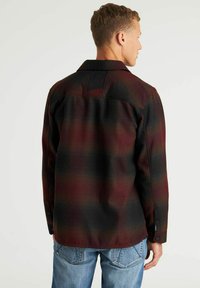 Geruite flanellen shirt in donkerrood en zwart, met een button-down kraag, lange mouwen en een gestructureerde stof met een kenmerkend patroon.