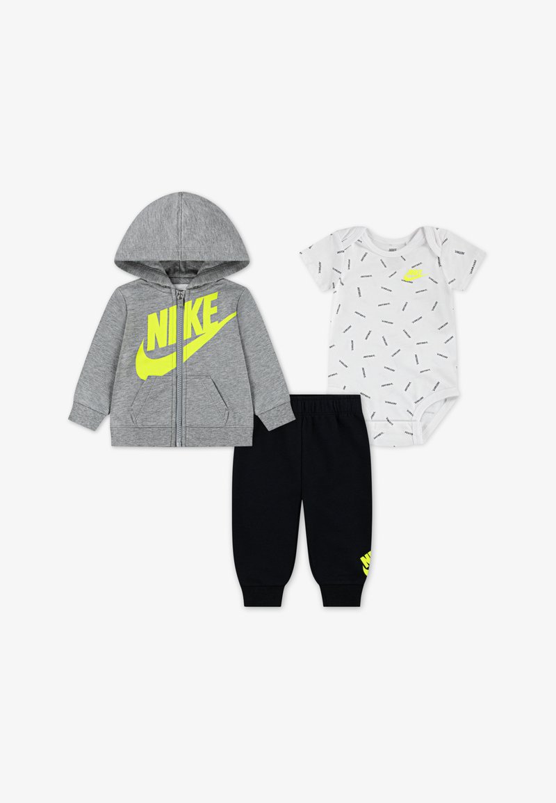 Siva jopa z zadrgo z neonsko rumenim logotipom Nike, bela bodi majica s kratkimi rokavi z teksturiranim potiskom in črne hlače jogger.