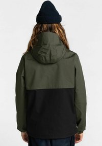 Hoodie-Jacke mit einem olivgrünen oberen Abschnitt und einem schwarzen unteren Abschnitt, aus leichtem Stoff gefertigt. Sie verfügt über lange Ärmel und einen lockeren Schnitt.