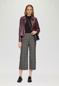 Burgunderfarbene Lederjacke, schwarzes Oberteil, graue karierte Culottes und schwarze Loafers. Merkmale sind ein Kragen, Knöpfe und eine Umhängetasche.