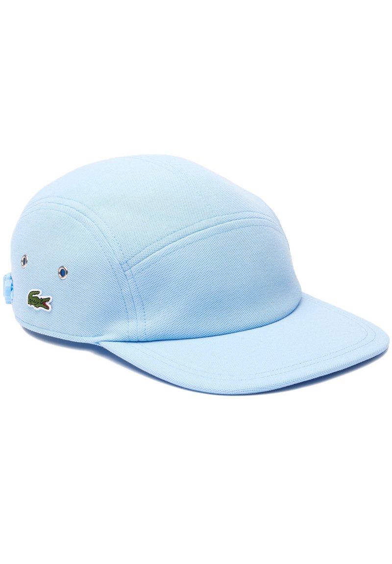 Gorra azul claro hecha de tela texturizada, con una corona redondeada, visor plano y un logotipo de cocodrilo verde bordado en el lateral.