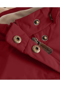Collar de chaqueta roja impermeable con botones a presión dorados, un acento de cuero marrón y una suave textura de forro beige.